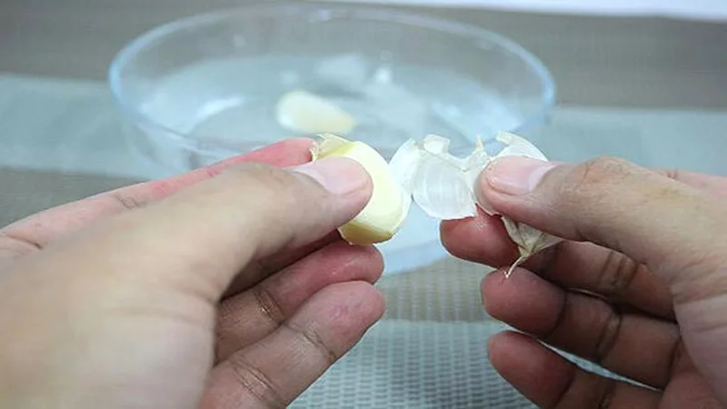 Chỉ cần ngâm tỏi trong nước ấm vài phút, vỏ sẽ mềm và dễ tuột khỏi tép.
